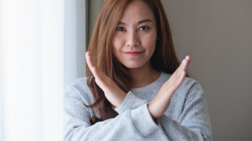 砂糖断ちを決意し、胸の前で腕をクロスさせて「NO（バツ）」のジェスチャーをする女性。砂糖への依存を断ち切るためのルールのイメージ。