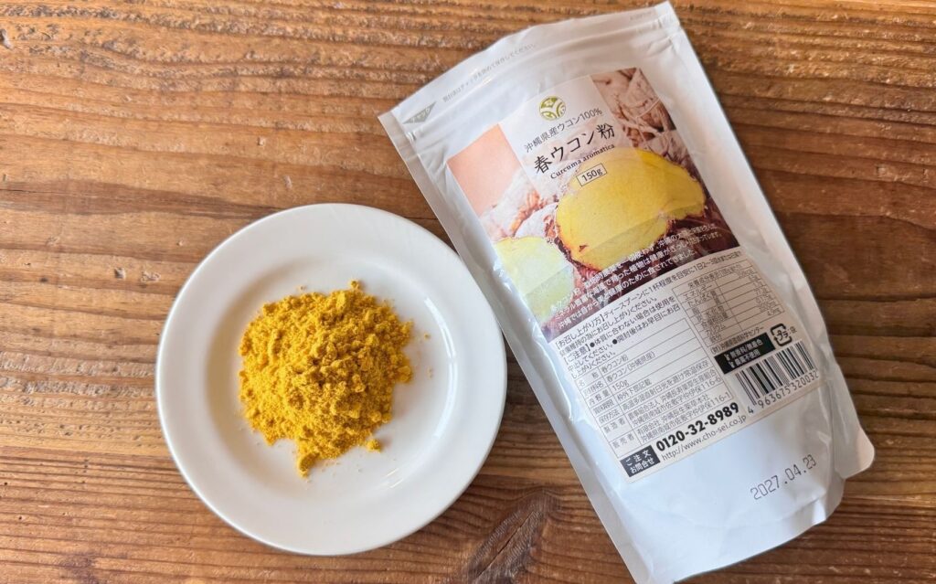 沖縄長生薬草本社の春ウコン粉150gのパッケージと小皿に出した淡い黄色の粉末