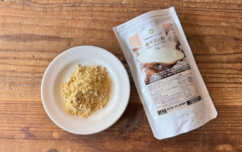 沖縄長生薬草本社の白ウコン粉50gのパッケージと小皿に出した淡黄白色の粉末