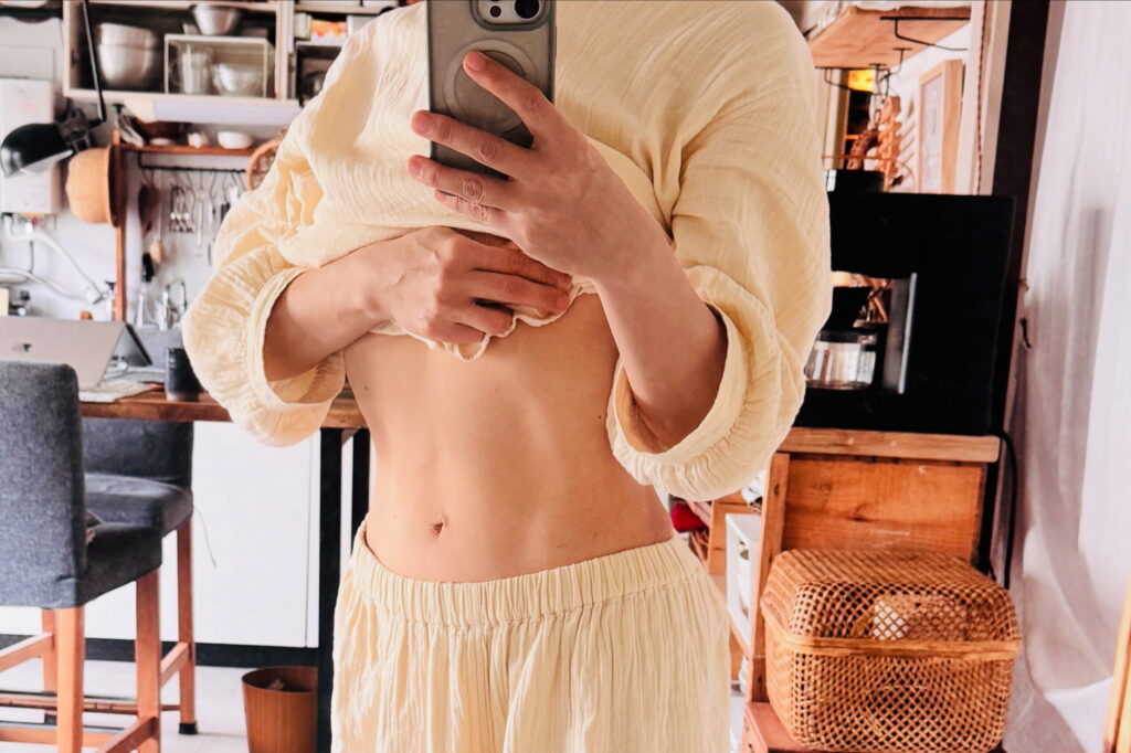 A 54-year-old's abs show vertical lines after three months of sobriety and Pilates. A selfie in the mirror.