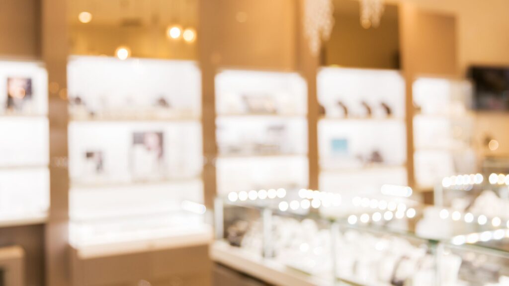 駅前のデパート内、華やかな照明とジュエリーのショーケースが並ぶ、少しぼやけた店内の風景