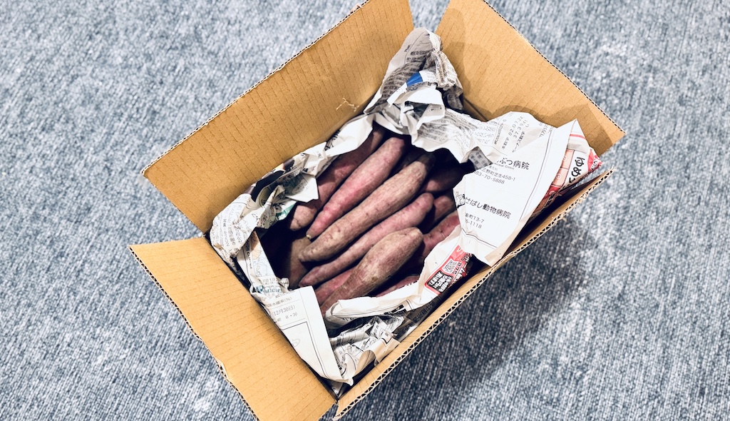 農家から直送で届いた、箱いっぱいの新鮮なさつまいも。スーパーよりも安全で安価な、こだわりのまとめ買いの様子。