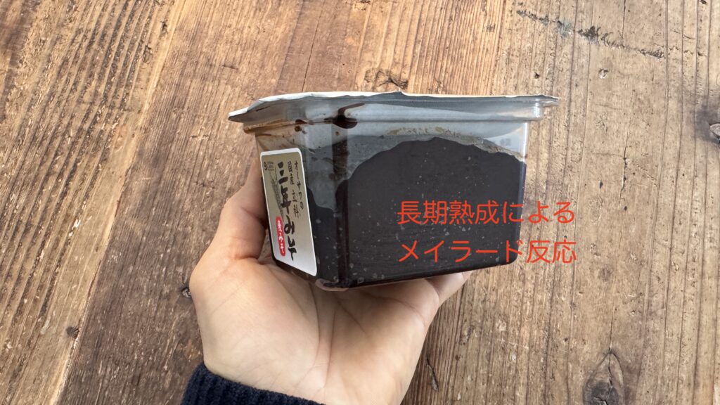 手に持った三年味噌のパッケージ。長期熟成によるメイラード反応で濃い茶色に変化している