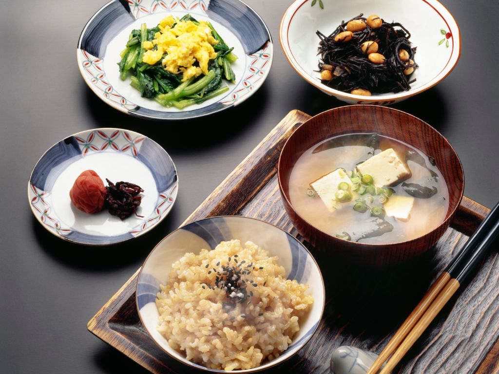 玄米、豆腐のお味噌汁、ひじきの煮物、青菜のお浸し、梅干しが並ぶ日本の伝統的な一汁三菜の食卓。添加物を使わず、素材本来の栄養を活かした「細胞投資」の基本となる食事。