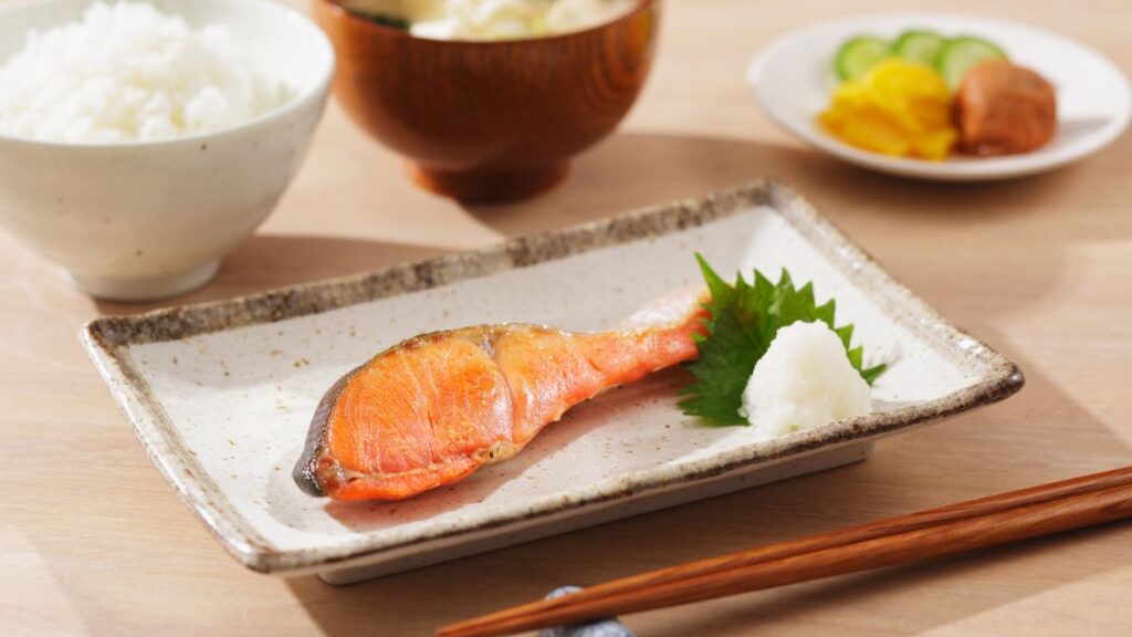 「日本の朝食の定番、焼き鮭定食。ごはん、味噌汁、漬物と並ぶこの一切れの鮭が、どこから来たものか考えたことはありますか？」