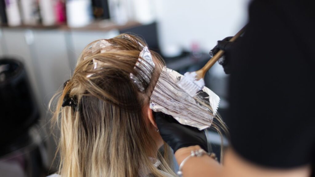 美容室でヘアカラーの施術を受ける女性。染料が頭皮に直接触れている