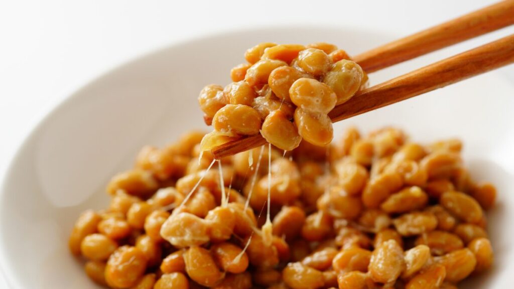 箸で持ち上げた糸引き納豆。納豆は日本が誇るスペルミジンの宝庫で、1パックあたり約2.5〜3mgのスペルミジンを含む世界的に注目される発酵食品。