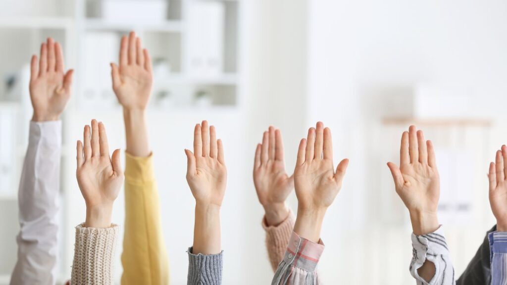 「一斉に手を挙げる人々。買い物のたびに私たちは『何を支持するか』を一票で示している。」